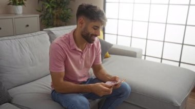 Modern oturma odasındaki bir kanepede otururken Meksika pesolarını sayan genç adam.
