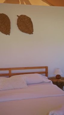 Afrika safari çadırında beyaz çarşafları olan rahat ahşap bir yatak, kırsal bir dekor ve doğa kampı macerasında lambalı bir komodinin yer aldığı bir yatak..