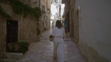 Polignano 'nun büyüleyici caddelerinde yürüyen genç bir kısrak, puglia, İtalya, tarihi taş duvarlar ve canlı yeşilliklerle Avrupa sokaklarının özünü yakalıyor..