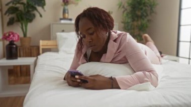 Yatak odasında pijama giyerken akıllı telefon kullanan yorgun bir kadın.