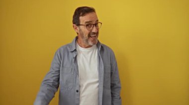 İspanyol orta yaşlı, gözlüklü, parlak fikirli, mutlu ve başarılı, izole edilmiş sarı arka planda duran bir adam.