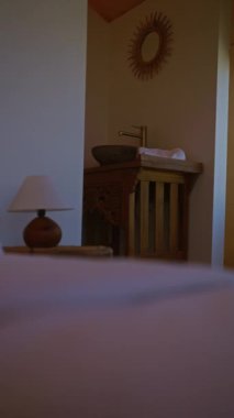 Ahşap lavabosu, aynası ve lambası olan taşra banyosu geleneksel bir tasarımı ön plana çıkarıyor..