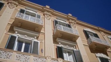 Puglia 'daki eski bir İtalyan binasının güzel mimari cephesi, süslü balkonları, pencereleri ve açık mavi gökyüzünün altında karmaşık tasarımları var..
