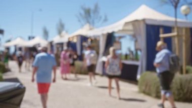 Mallorca 'da açık hava pazarında yürüyen insanlar. Parlak mavi gökyüzünün altında çadırları ve satıcıları var.
