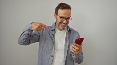 İspanyol orta yaşlı bir adam, elinde akıllı bir telefonla gururlu bir gülümsemeyle kendini işaret ediyor.