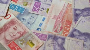 İsveç banknotları rengarenk tasarımlar ve portreler içeren çeşitli banknotlar, İsveç 'te para birimi ve finansal temaları gösteren düz bir yüzeye saçılmıştır..