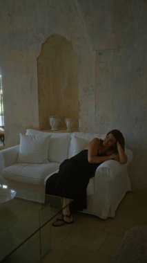 Güzel bir İspanyol kadın beyaz bir kanepede dinleniyor tipik bir İtalyan masserisi tarzı evde..