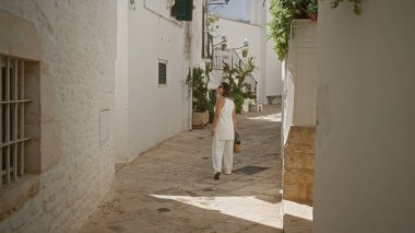 Genç bir İspanyol kadın yaz mevsiminde Puglia, İtalya 'da Locorotondo' nun güzel beyaz sokaklarında yürüyor..