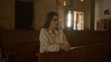 Genç İspanyol kadın dingin bir İtalyan kilisesinde dua ediyor, güzelliğini ve kutsal, barışçıl Hristiyan atmosferini vurguluyor..