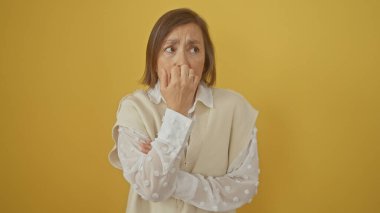 Olgun bir kadın endişeli bir ifadeyle sarı arka plan, zarif, gösterişsiz.