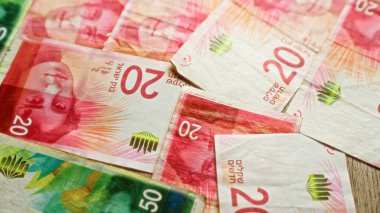 Renkli israeli şekel banknotları düz bir yüzeye rastgele dizilmiş.