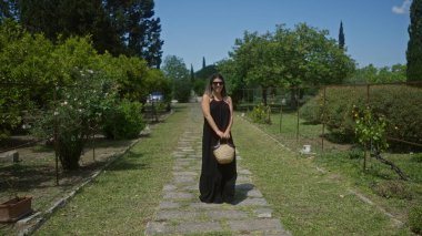 Güzel, genç, İspanyol bir kadın güneşli bir günde güneşli bir villada ya da masseride yeşilliklerle çevrili Puglia, İtalya 'da yemyeşil bir bahçede duruyor..