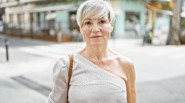 Şehir sokağında duran gri saçlı, olgun bir İspanyol kadının portresi..