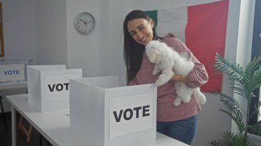 Arka planda Meksika bayrağı olan bir köpek taşıyan gülümseyen bir kadın..
