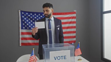 A hispanic man in a suit examines a ballot at an american electoral booth with us flags clipart