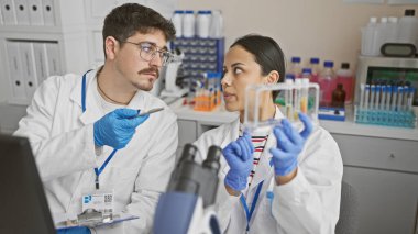 Man and woman scientists analyzing a test tube together in a laboratory setting. clipart