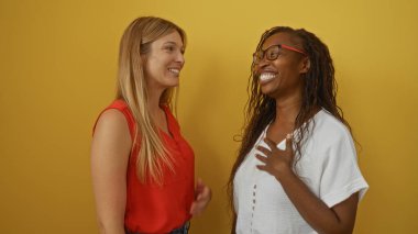 Women sharing a joyful moment together over an isolated yellow background, showcasing friendship and happiness. clipart