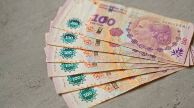 Arjantin 'in para, finans ve ekonomik konseptini ayrıntılı olarak gösteren somut bir yüzey üzerinde 100 pesoluk Arjantin banknotları.