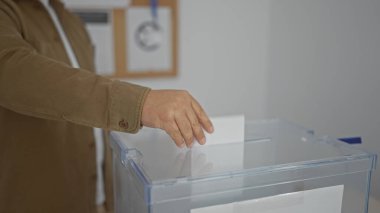 Hispanik adam kapalı seçim okulundaki oy sandığında oy kullanıyor.