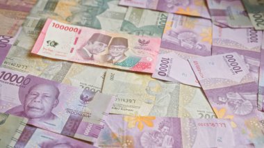 Indonesian rupiah banknotes spread out showing various denominations including 100000, 50000, 20000, and 10000 in a colorful, detailed manner. clipart