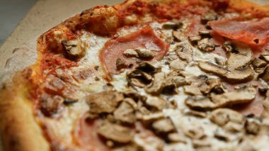 Mantar ve prosciutto ile kaplanmış lezzetli pizza, yakın çekim yiyecek fotoğrafında altın kabuk ve erimiş peynir gösteriliyor.