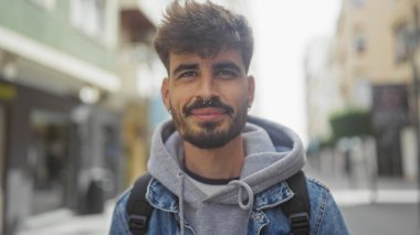 Sakallı yakışıklı İspanyol adam, şehir sokaklarında gülümsüyor