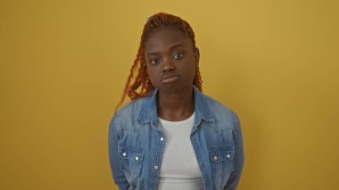 Sarı arka planda kot giyen Afrikalı Amerikalı kadın