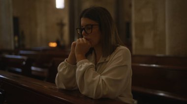 Genç bir İspanyol kadın, İtalya 'da güzel bir kilisede sessizce dua ediyor. Kutsal mekanın dingin Hristiyan atmosferini yansıtıyor..