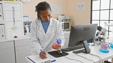 Afrika kökenli Amerikalı kadın bilim adamı bir laboratuvar ortamında bir örneği analiz ediyor..