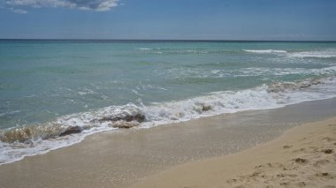 Salento, puglia, İtalya 'daki sakin pescoluse plajı, berrak mavi gökyüzünün altında yumuşak dalgaları ve altın kumu olan sakin bir deniz manzarasına ev sahipliği yapar..