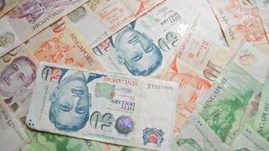 Singapur doları banknotları çeşitli banknotlara dağılmış canlı tasarımlar sergiliyor ve Singapur 'un para birimini temsil ediyor..
