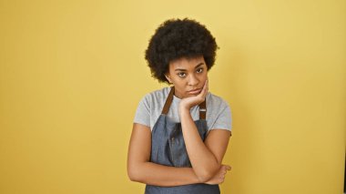 Sarı duvara yaslanmış kıvırcık saçlı düşünceli Afrikalı Amerikalı kadın..