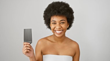 Kıvırcık saçlı mutlu Afro-Amerikalı kadın beyaz izole bir arka plana tarak tutuyor.