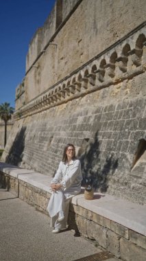 Genç bir İspanyol kadın Puglia, İtalya 'daki tarihi Bari kalesinin duvarlarında güneşli bir günün tadını çıkarıyor..
