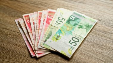 İsrail şekel banknotları, İsrail 'den gelen çeşitli mezhepleri gösteren, finansal konsept ve para birimi temasını gösteren ahşap bir yüzeye yerleştirilmiş..
