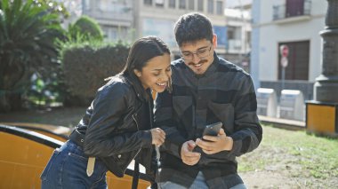 Şehirdeki bir erkek ve kadın, akıllı bir telefonla açık havada bağ kuruyor, modern bir ilişkide teknoloji sergiliyor..