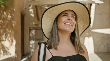 Gülümseyen esmer bir kadın Dubai 'de geleneksel bir çorbayı geniş kenarlı bir şapkayla keşfediyor..