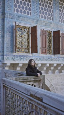 Siyahlar içinde gülümseyen bir kadın İstanbul 'daki tarihi topkapı sarayını geziyor..