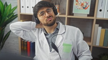 Klinikte sakallı, kulaklık takan genç bir Arap mola sırasında dinleniyor.