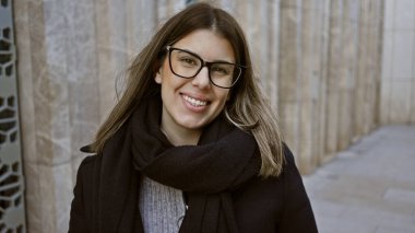 Gözlüklü, gülümseyen genç bir kadın tarihi İstanbul caddesinde duruyor. Seyahat ve kentsel güzelliğin vücut bulmuş hali..