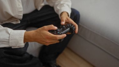 Oturma odasında otururken bir kontrolörle video oyunu oynayan İspanyol bir genç.
