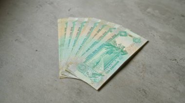 Birleşik Arap Emirlikleri 'nin Dirham banknotları somut bir yüzeye yelpaze gibi yayıldı ve para birimini finansal bağlamda gösterdi..