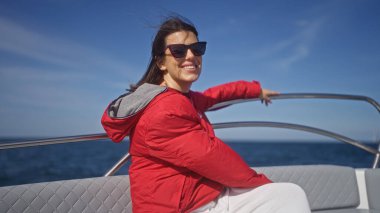 Genç bir İspanyol kadın polignano 'nun berrak mavi sularında güneşli bir günün tadını çıkarıyor. Bir kısrak, puglia, İtalya, neşeyle gülümsüyor. Kırmızı ceketi deniz ve gökyüzüne karşı zıt düşerken..