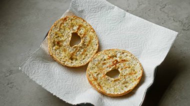 Kağıt havluya tereyağlı simit yarımları konmuş beton yüzeyde doğal ışıkta.