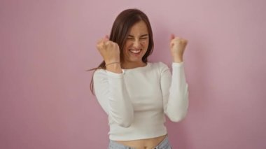 Kazanan genç bir kadın mutlu ve başarı için heyecanlı bir şekilde duran pembe arka planda kutlama çığlığı atan sarışın.