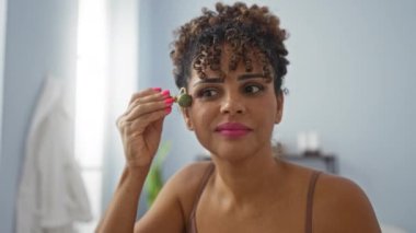 Sağlık odasındaki yüz masajı için kaplıcada yeşim taşı kullanan bir kadın. İç mekanda güzellik ve kendine bakımı ön plana çıkarıyor.