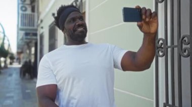 Genç bir Afrikalı Amerikalı, bir şehir sokağında selfie çekiyor..