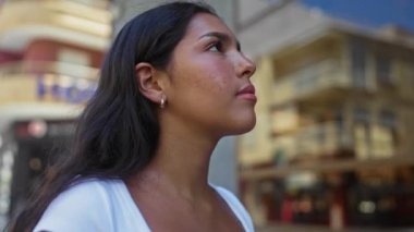 Şehir caddesinde gözleri kapalı, rahat ve rahat görünen, modern binalarla dolu bir arka planda duran genç kadın.