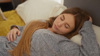 Genç sarışın bir kadın yatak odasında rahat bir yatakta uyurken evcil köpeği yanında dikiliyor..