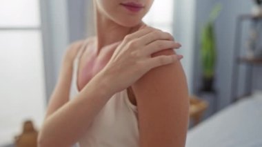 Genç bir kadın spa odasında nazikçe omzuna dokunuyor. Huzur veren bir sağlık ortamında cildini renklendiriyor.